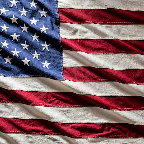 A waving US flag with red and white stripes and a blue field of white stars.