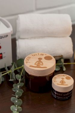 A spa setup: Spacequip heater, glowing candles, eucalyptus decor, and massage oil containers on a wooden table.