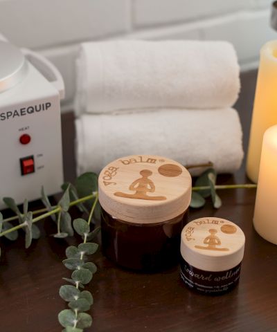 A spa setup: Spacequip heater, glowing candles, eucalyptus decor, and massage oil containers on a wooden table.