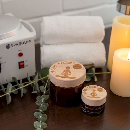 Spa scene with a warming device, lit candles, and eucalyptus stems on a table.