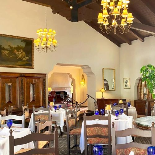 A cozy living room with a wooden coffee table, shelves, plants, and family photos; a bright sunny vibe with warm decor.