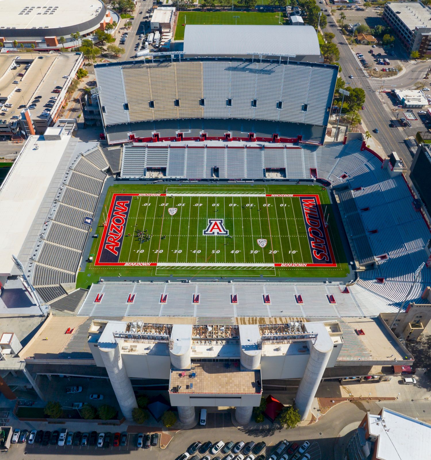 Aerial view of a football stadium with a green field and score markings, showing the Arizona logo and goals.