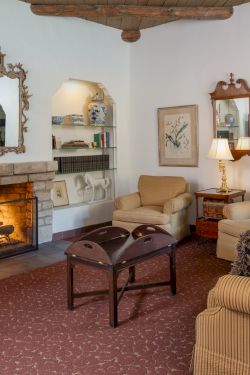 Cozy living room with a lit fireplace, built-in shelves, framed art, cream and beige furniture, and warm ambient lighting.