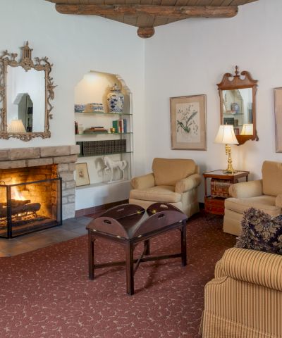 Cozy living room with a lit fireplace, built-in shelves, framed art, cream and beige furniture, and warm ambient lighting.