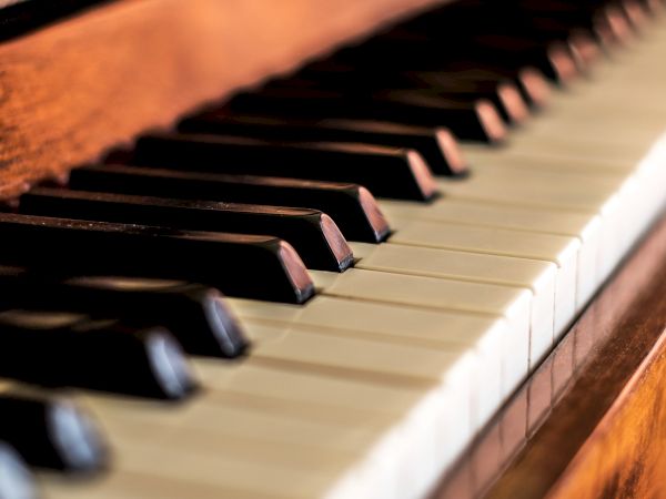 A close-up of piano keys with warm wooden frame, showing black and white keys stretching into the distance.