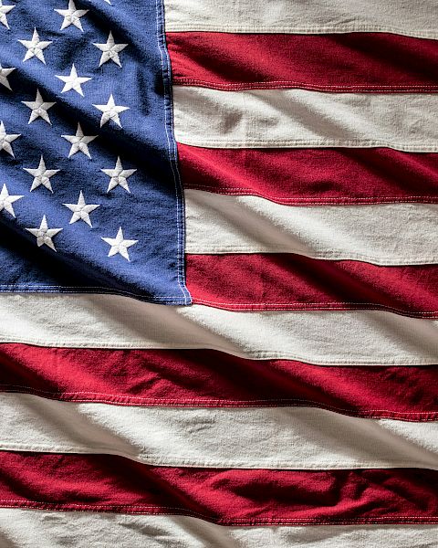 A waving US flag with red and white stripes and a blue field of white stars.