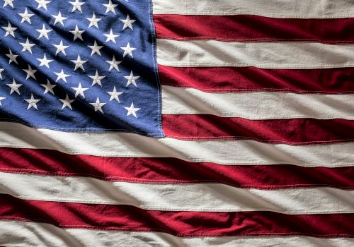 A waving US flag with red and white stripes and a blue field of white stars.