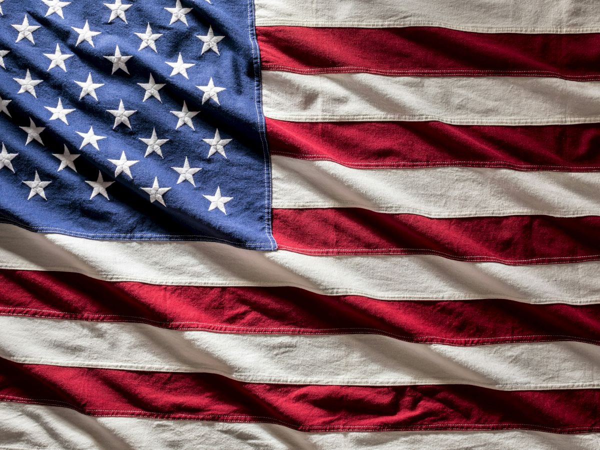 The United States flag, wavy fabric with stars and red-and-white stripes, patriotic imagery.