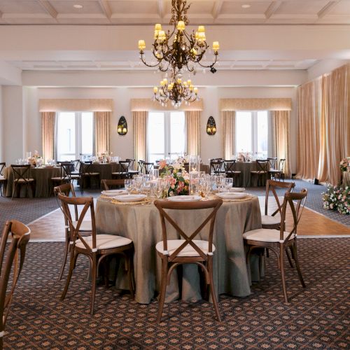 Tucson Ballroom set with round tables wooden chairs, and ornate chandeliers under gold curtains.