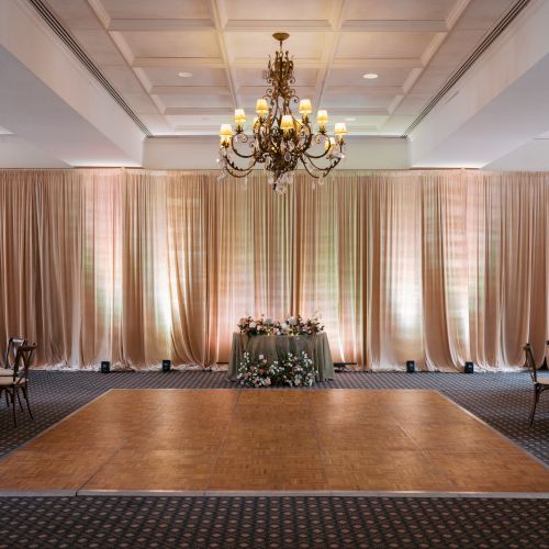 Tucson Ballroom with a grand chandelier, and shimmering beige curtains.
